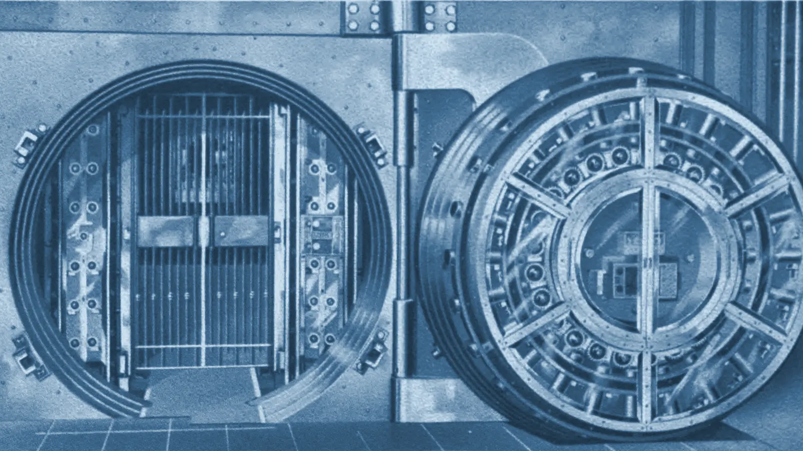 Two circular steel vault doors in a strongroom, one standing open.